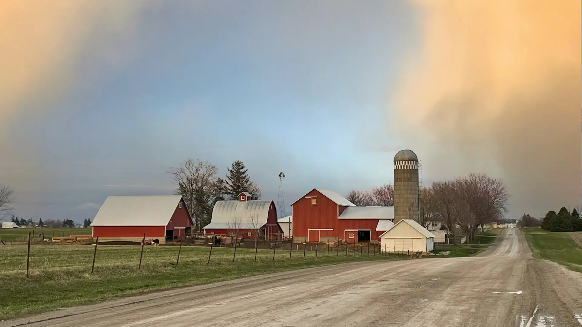 Zandweg naar een boerderij met rode schuren en een silo onder een lucht na een onweer, Johnson County, Iowa — Urbandale